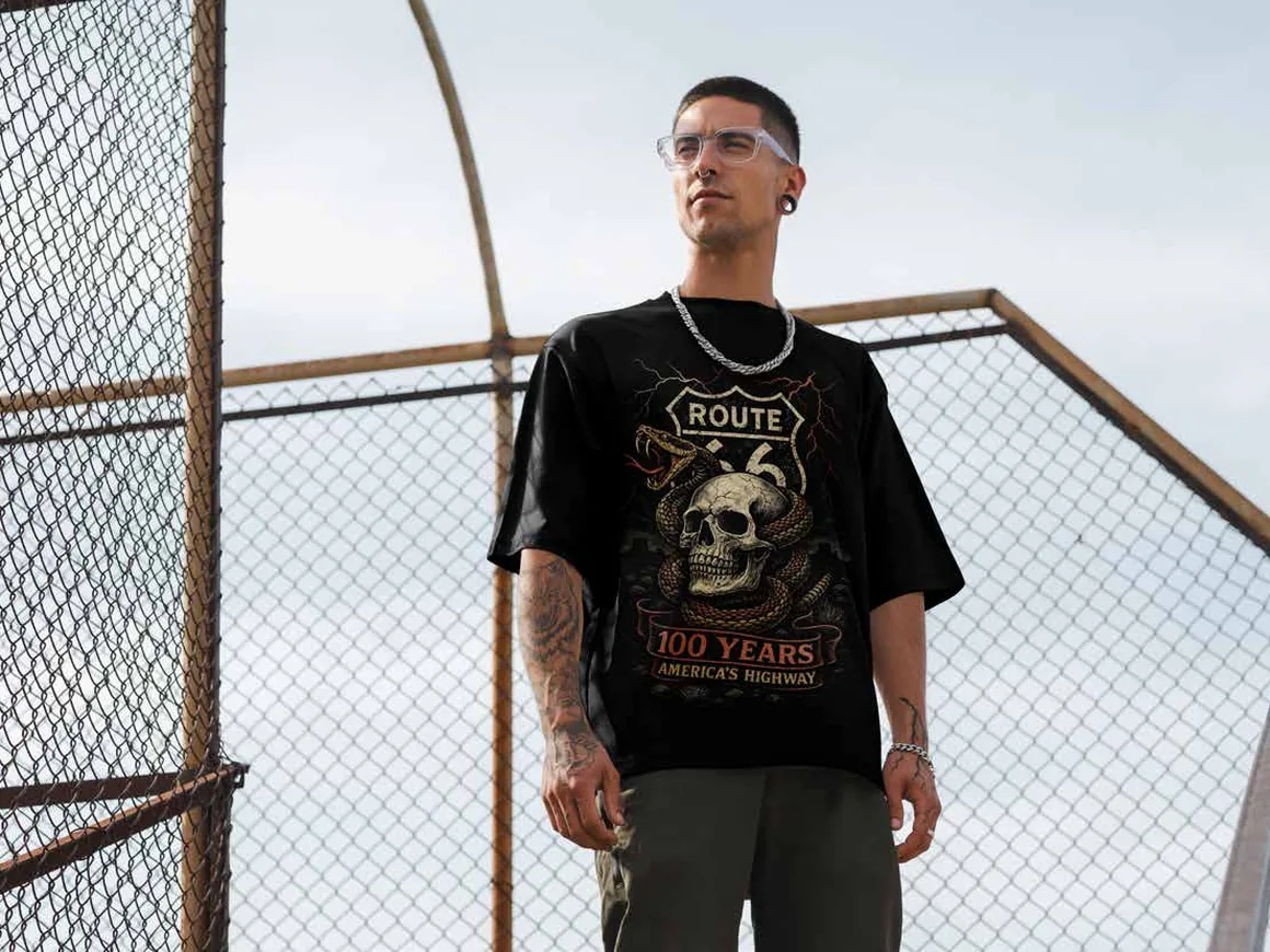 A man by a wire fence in a 100 Years of America’s Highway T-shirt