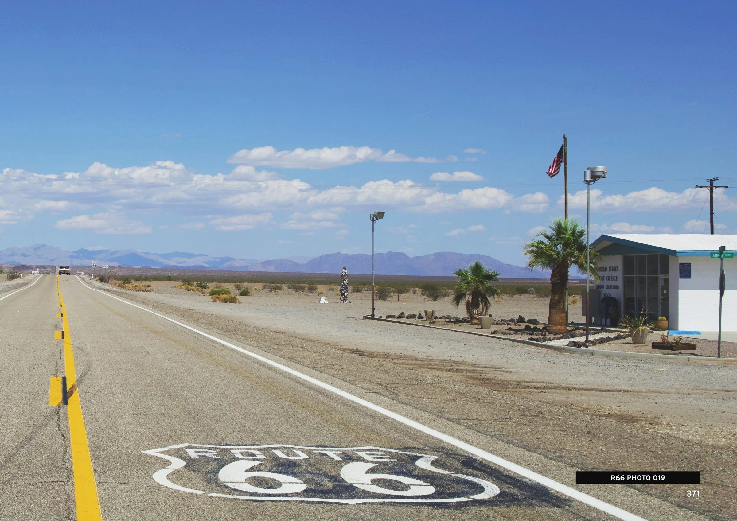 ROUTE 66 shield painted on the highway with desert mountains beyond